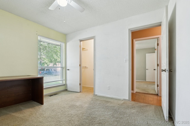 8202 S Ash Pl, Broken Arrow, OK 74011 - unfurnished bedroom with carpet flooring, a textured ceiling, a walk in closet, and a ceiling fan