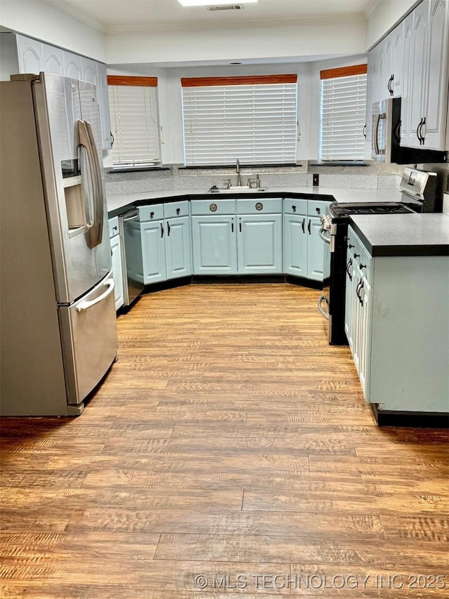 5101 S Spruce Dr, Sand Springs, OK 74063 - kitchen with stainless steel appliances, light wood-style floors, dark countertops, and ornamental molding