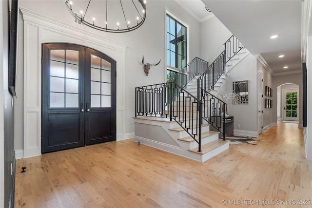3207 E 44th St, Tulsa, OK 74105 - foyer featuring arched walkways, wood finished floors, a chandelier, ornamental molding, and stairway