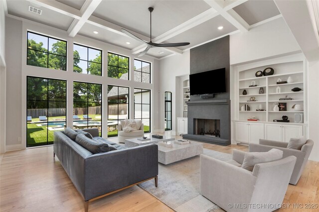3207 E 44th St, Tulsa, OK 74105 - living room with a high ceiling, a ceiling fan, a fireplace with raised hearth, coffered ceiling, and light wood-type flooring