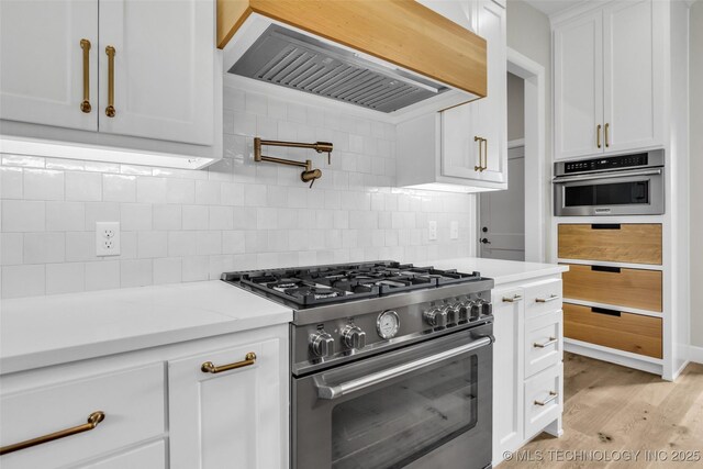 6364 N Blue Sage Dr, Owasso, OK 74055 - kitchen featuring appliances with stainless steel finishes, premium range hood, white cabinetry, backsplash, and light wood-style floors