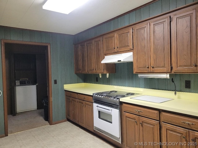 1296 Robin Hood Rd, Eufaula, OK 74432 - kitchen with under cabinet range hood, electric range, washer / dryer, light flooring, and light countertops