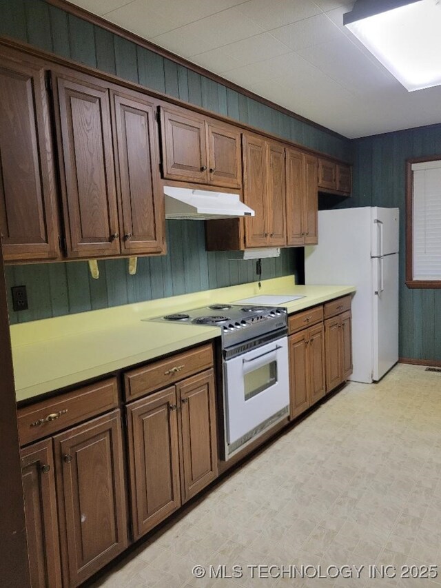 1296 Robin Hood Rd, Eufaula, OK 74432 - kitchen featuring white appliances, under cabinet range hood, wooden walls, light floors, and light countertops