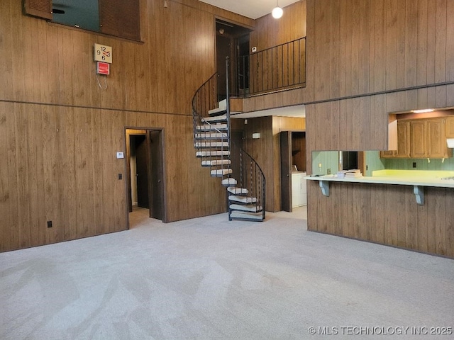 1296 Robin Hood Rd, Eufaula, OK 74432 - unfurnished living room featuring light colored carpet, a high ceiling, stairway, wood walls, and washer / clothes dryer