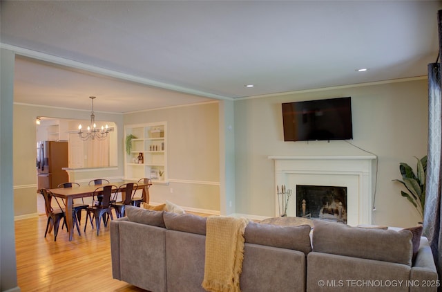 2328 S Delaware Ct, Tulsa, OK 74114 - living area featuring a chandelier, light wood-style flooring, crown molding, a fireplace, and built in shelves