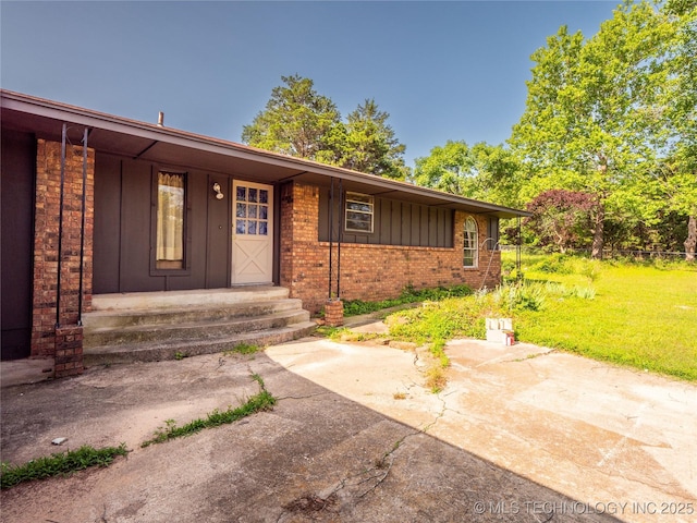 1015 Diehl Ln, Hartshorne, OK 74547 - entrance to property featuring brick siding, board and batten siding, covered porch, and a lawn
