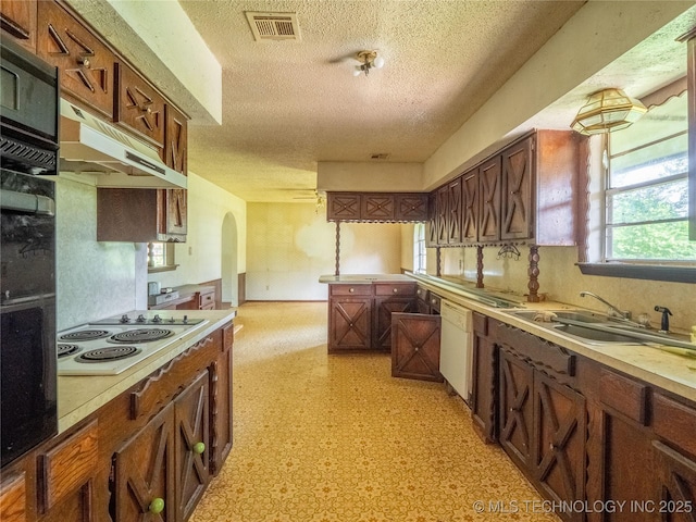 1015 Diehl Ln, Hartshorne, OK 74547 - kitchen featuring white appliances, a textured ceiling, arched walkways, under cabinet range hood, and light flooring