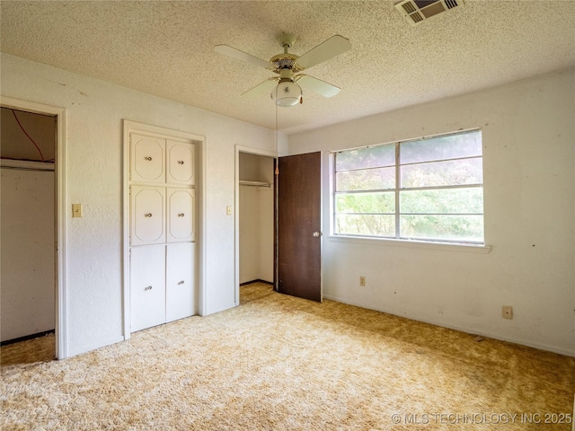 1015 Diehl Ln, Hartshorne, OK 74547 - unfurnished bedroom featuring multiple closets, carpet, a textured ceiling, and ceiling fan