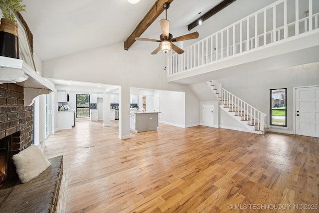 7927 S 86th E Ave, Tulsa, OK 74133 - unfurnished living room featuring a brick fireplace, high vaulted ceiling, a ceiling fan, stairway, and beam ceiling