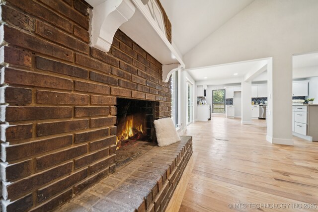 7927 S 86th E Ave, Tulsa, OK 74133 - unfurnished living room featuring light wood-type flooring, vaulted ceiling, and a fireplace
