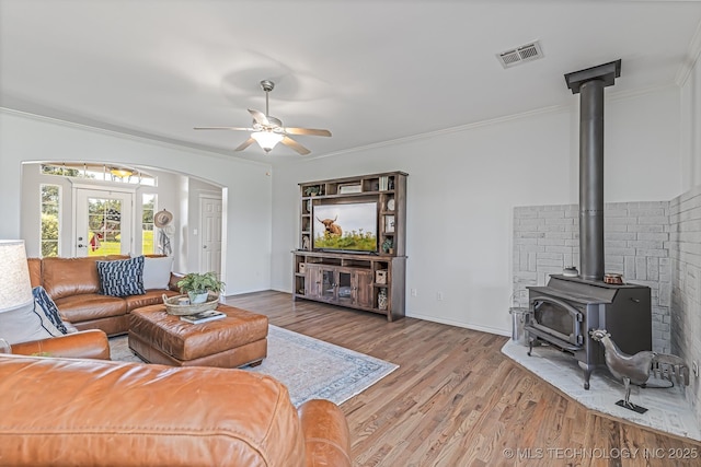 330 Loma Vista Ln, Skiatook, OK 74070 - living area featuring a wood stove, wood finished floors, arched walkways, a ceiling fan, and ornamental molding