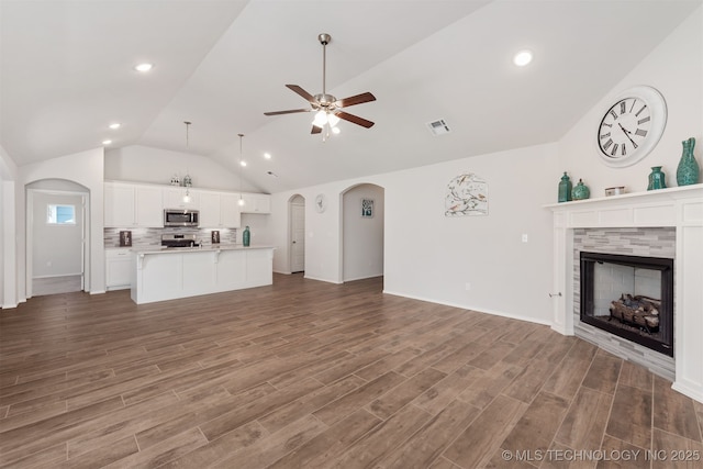 1813 E Van Buren Pl, Broken Arrow, OK 74011 - unfurnished living room with vaulted ceiling, arched walkways, a fireplace, ceiling fan, and wood finished floors