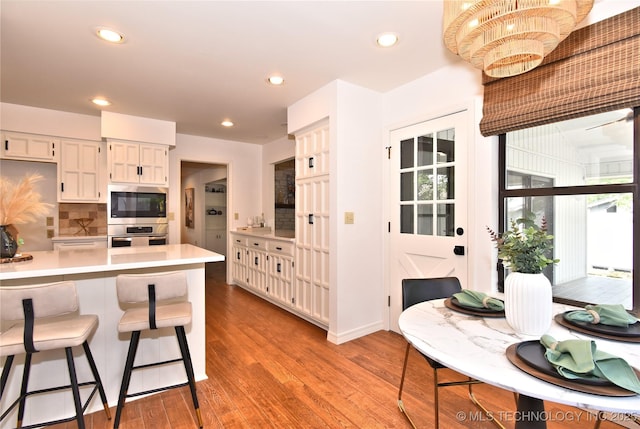 8504 S Winston Ave, Tulsa, OK 74137 - kitchen featuring light countertops, stainless steel appliances, a breakfast bar, light wood-style flooring, and tasteful backsplash