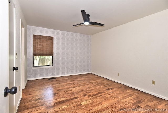 8504 S Winston Ave, Tulsa, OK 74137 - unfurnished room featuring wallpapered walls, ceiling fan, wood finished floors, and an accent wall