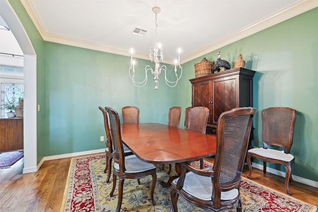 4733 S 167th E Pl, Tulsa, OK 74134 - dining space featuring a chandelier, light wood-style floors, crown molding, and arched walkways