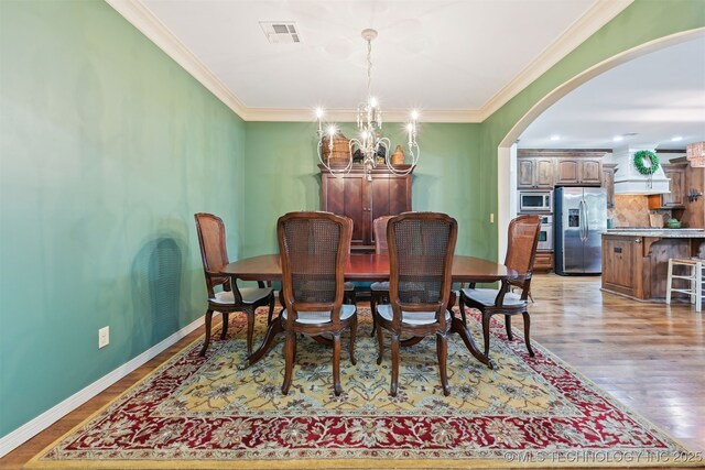 4733 S 167th E Pl, Tulsa, OK 74134 - dining space with arched walkways, a chandelier, ornamental molding, and light wood-type flooring