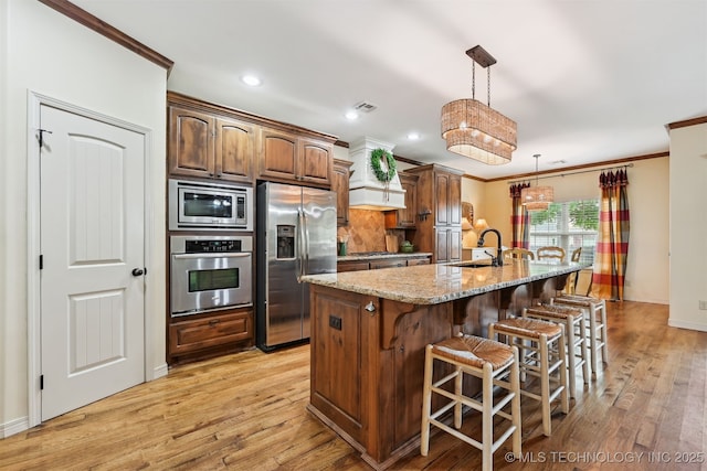 4733 S 167th E Pl, Tulsa, OK 74134 - kitchen featuring appliances with stainless steel finishes, crown molding, light wood-type flooring, light stone countertops, and a breakfast bar area