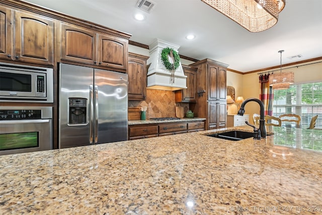 4733 S 167th E Pl, Tulsa, OK 74134 - kitchen featuring appliances with stainless steel finishes, ornamental molding, light stone counters, backsplash, and a chandelier