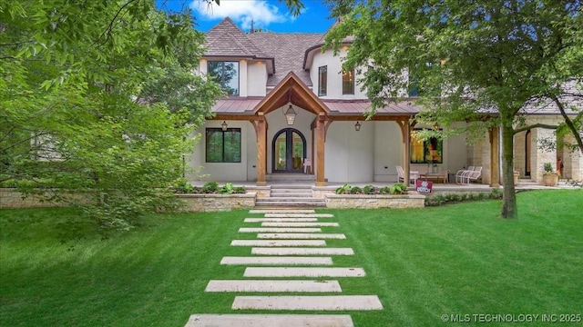 20565 E Clear Brook Rd, Owasso, OK 74055 - tudor house featuring a standing seam roof, stucco siding, a front lawn, a metal roof, and french doors
