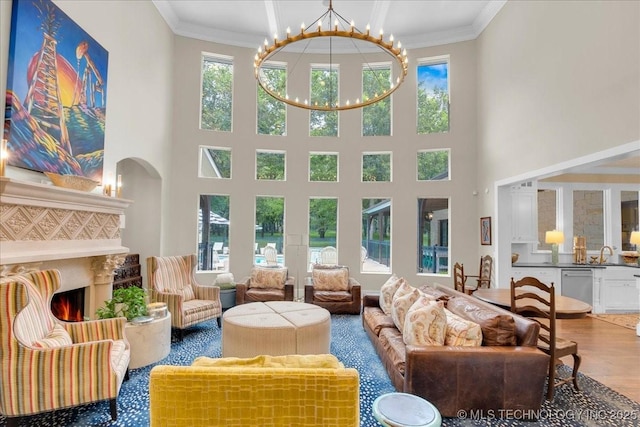 20565 E Clear Brook Rd, Owasso, OK 74055 - living area featuring a chandelier, a towering ceiling, wood finished floors, ornamental molding, and a lit fireplace