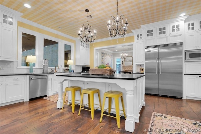 20565 E Clear Brook Rd, Owasso, OK 74055 - kitchen featuring built in appliances, a chandelier, ornamental molding, a kitchen island, and white cabinets