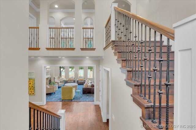 20565 E Clear Brook Rd, Owasso, OK 74055 - stairway featuring a towering ceiling, crown molding, wood finished floors, and recessed lighting