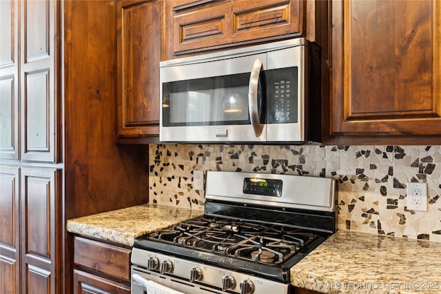 14400 E Willow Way, Claremore, OK 74019 - kitchen featuring appliances with stainless steel finishes, tasteful backsplash, and light stone counters