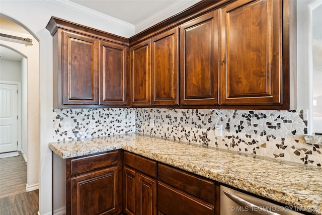 14400 E Willow Way, Claremore, OK 74019 - kitchen with stainless steel dishwasher, tasteful backsplash, light stone countertops, arched walkways, and wood finished floors