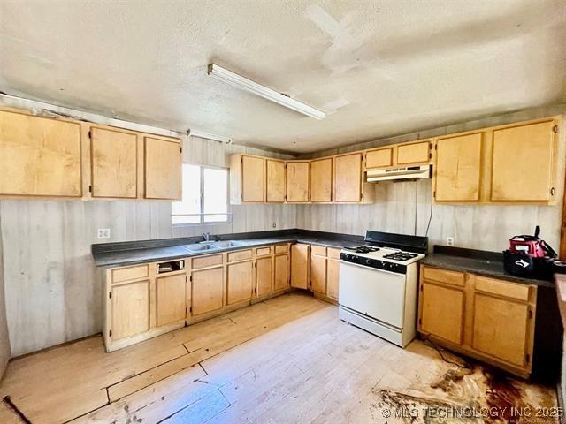 100 W Walnut Ave, Coalgate, OK 74538 - kitchen featuring white gas range oven, under cabinet range hood, dark countertops, and a textured ceiling
