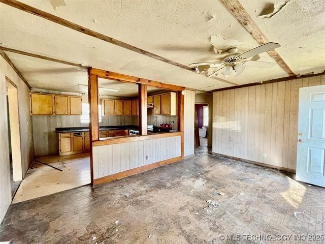 100 W Walnut Ave, Coalgate, OK 74538 - unfurnished living room with a textured ceiling, wood walls, and a ceiling fan