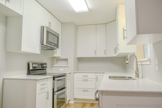 3180 E 2090th Rd, Hugo, OK 74743 - kitchen featuring appliances with stainless steel finishes, light wood finished floors, white cabinetry, and light stone counters