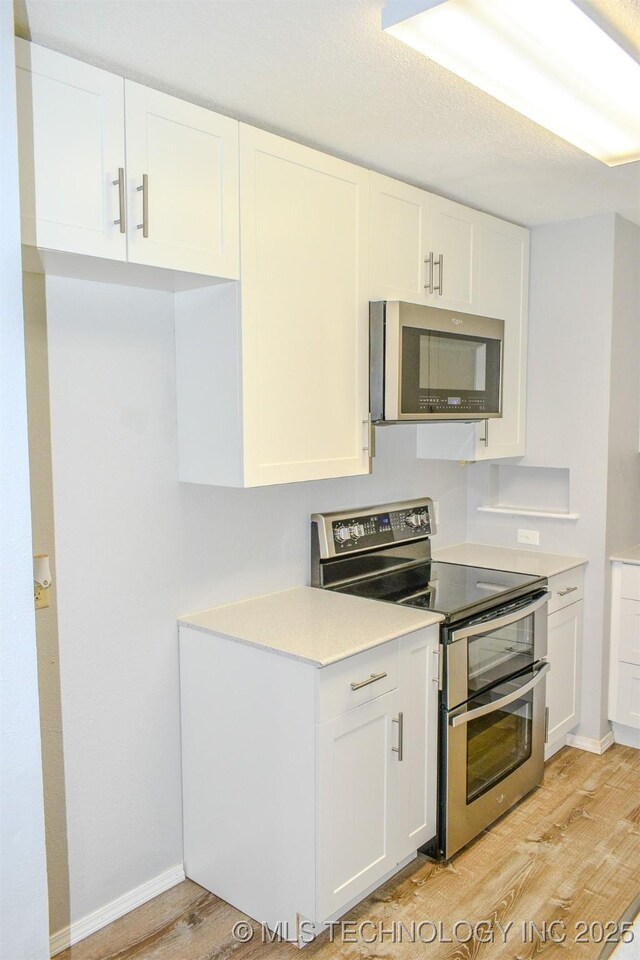 3180 E 2090th Rd, Hugo, OK 74743 - kitchen with stainless steel appliances, light wood-style floors, white cabinetry, and light countertops