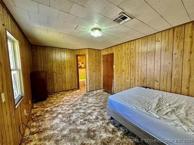 1305 7th Ave NW, Ardmore, OK 73401 - bedroom featuring carpet flooring and wood walls