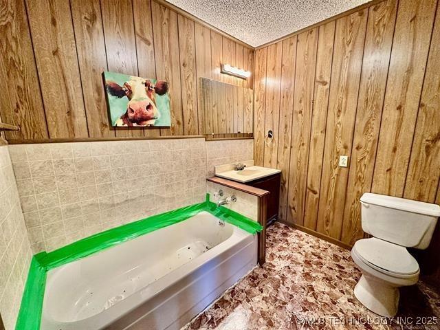 1305 7th Ave NW, Ardmore, OK 73401 - full bathroom featuring a textured ceiling, wood walls, a tub to relax in, and vanity
