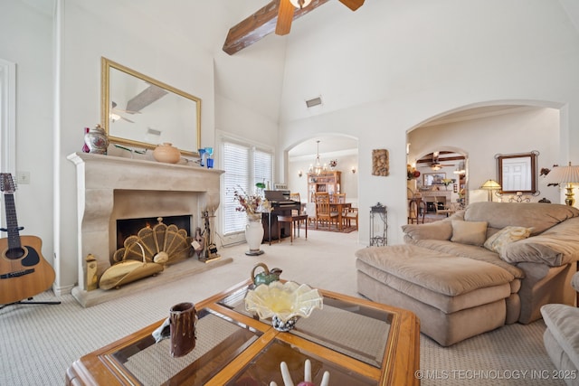 7721 E 101st Pl, Tulsa, OK 74133 - carpeted living area with arched walkways, a ceiling fan, high vaulted ceiling, a fireplace with raised hearth, and a chandelier