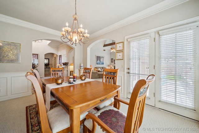 7721 E 101st Pl, Tulsa, OK 74133 - dining area featuring arched walkways, light carpet, ornamental molding, a chandelier, and wainscoting