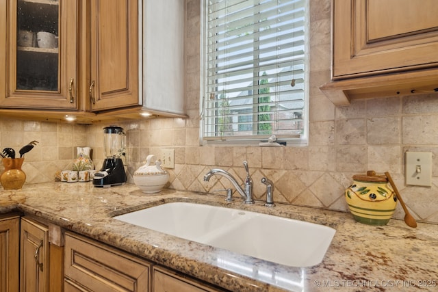 7721 E 101st Pl, Tulsa, OK 74133 - kitchen with backsplash, light stone counters, glass insert cabinets, and brown cabinetry