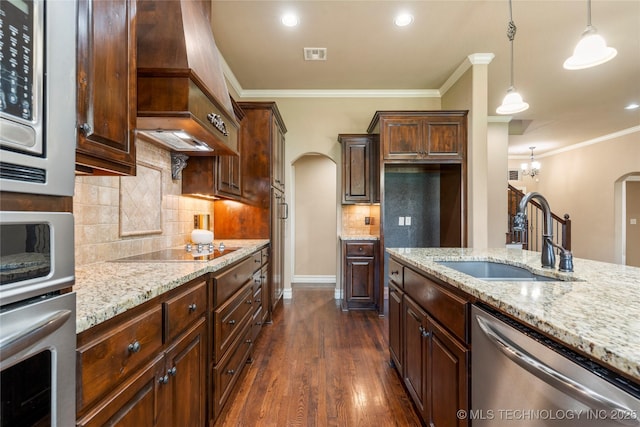 425 W 128th St S, Jenks, OK 74037 - kitchen featuring arched walkways, appliances with stainless steel finishes, custom range hood, light stone countertops, and crown molding