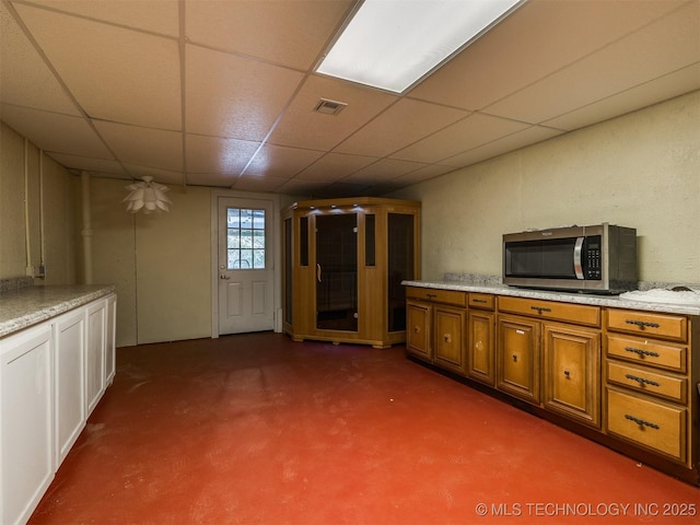 109 E Bk 800th Rd, Stigler, OK 74462 - kitchen featuring stainless steel microwave, brown cabinets, and a drop ceiling