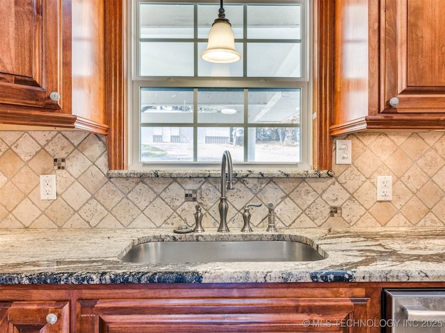 109 E Bk 800th Rd, Stigler, OK 74462 - kitchen with tasteful backsplash, light stone countertops, brown cabinetry, and hanging light fixtures