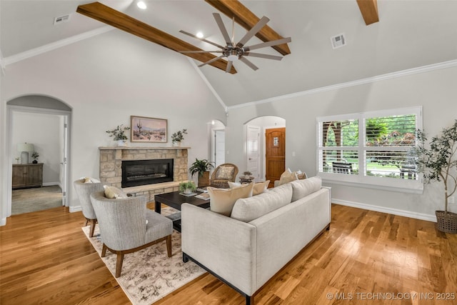7380 Royalwood Way, Tulsa, OK 74131 - living area featuring arched walkways, a stone fireplace, a ceiling fan, high vaulted ceiling, and beam ceiling