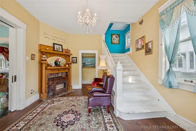 415 S 13th St, Muskogee, OK 74401 - stairway featuring wood finished floors, a chandelier, a brick fireplace, and healthy amount of natural light