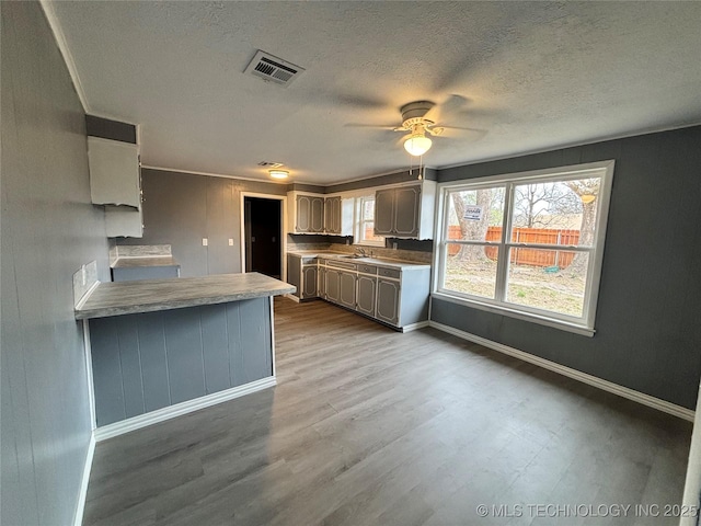 305 NW 4th St Unit 1/2, Wilburton, OK 74578 - kitchen featuring dark wood finished floors, a ceiling fan, a peninsula, a textured ceiling, and light countertops