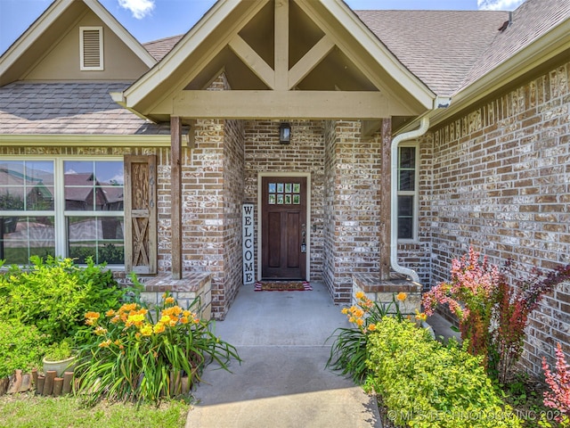 7616 E 84th St, Owasso, OK 74021 - doorway to property featuring brick siding and roof with shingles