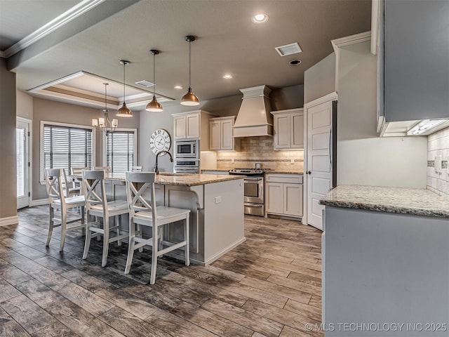 7616 E 84th St, Owasso, OK 74021 - kitchen featuring appliances with stainless steel finishes, custom exhaust hood, tasteful backsplash, wood finished floors, and recessed lighting