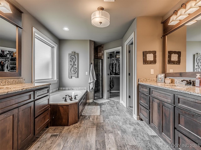 7616 E 84th St, Owasso, OK 74021 - bathroom with vanity, wood finished floors, a garden tub, a walk in closet, and recessed lighting