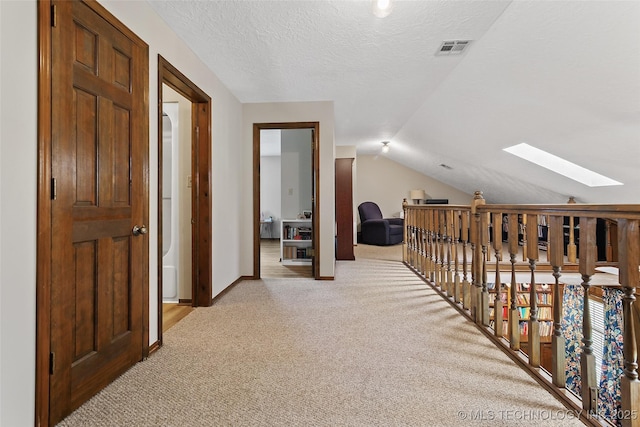 9644 Ew 19 Rd, Nowata, OK 74048 - hallway with a skylight, light carpet, vaulted ceiling, a textured ceiling, and an upstairs landing