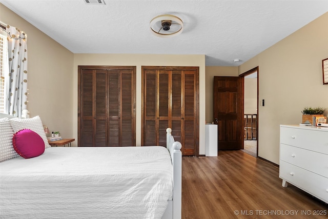 9644 Ew 19 Rd, Nowata, OK 74048 - bedroom featuring multiple closets, wood finished floors, and a textured ceiling