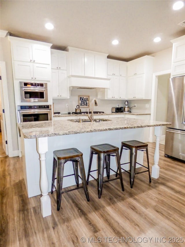 414467 E 1090th Rd, Checotah, OK 74426 - kitchen featuring stainless steel appliances, white cabinets, light wood-style floors, a breakfast bar, and recessed lighting