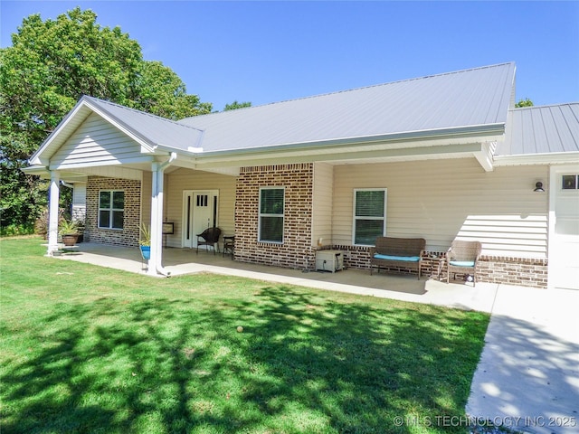 414467 E 1090th Rd, Checotah, OK 74426 - back of property featuring brick siding, a patio area, a lawn, and a metal roof